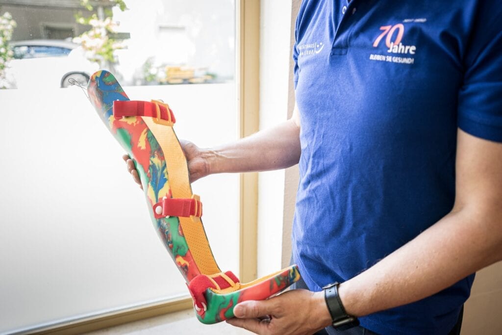 Mitarbeiter zeigt bunte Kinderprothese